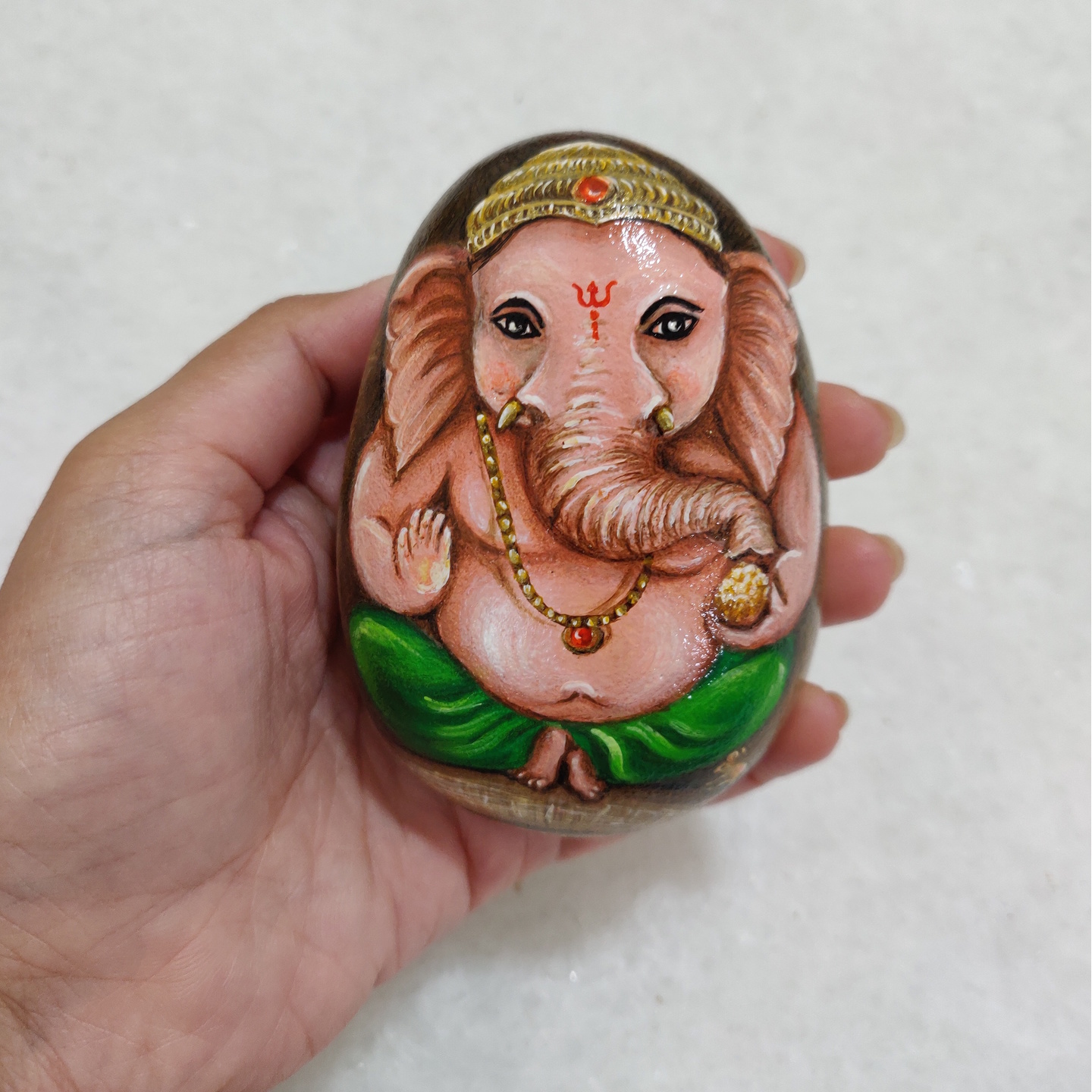 Lord Ganesha sitting in a conch shell hand painted on a rock for diwali